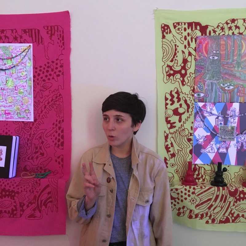a photo of the author in front of two neon tapestries